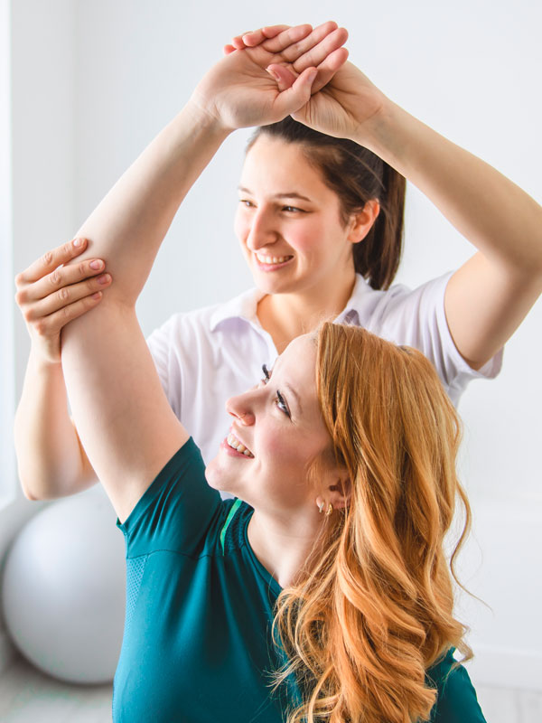 Therapeutin behandelt eine Patientin bei einer gezielten Übung für Schulter und Arm