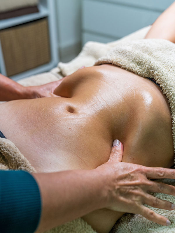Eine Patientin erhält eine sanfte Lymphdrainage im Hüft und Beckenbereich auf einer Behandlungsliege
