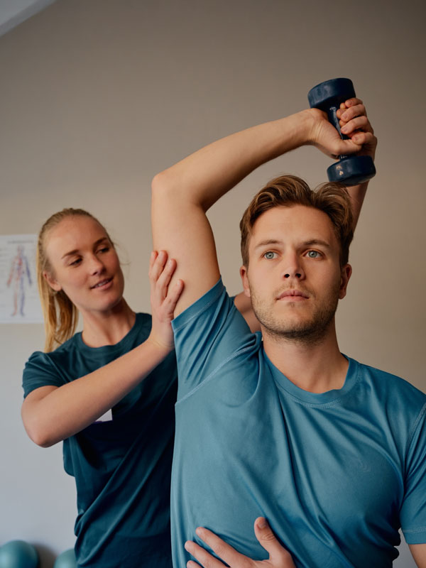 Patient erhält unter Anleitung einer Therapeutin eine manuelle Therapie für Schulter und Arm