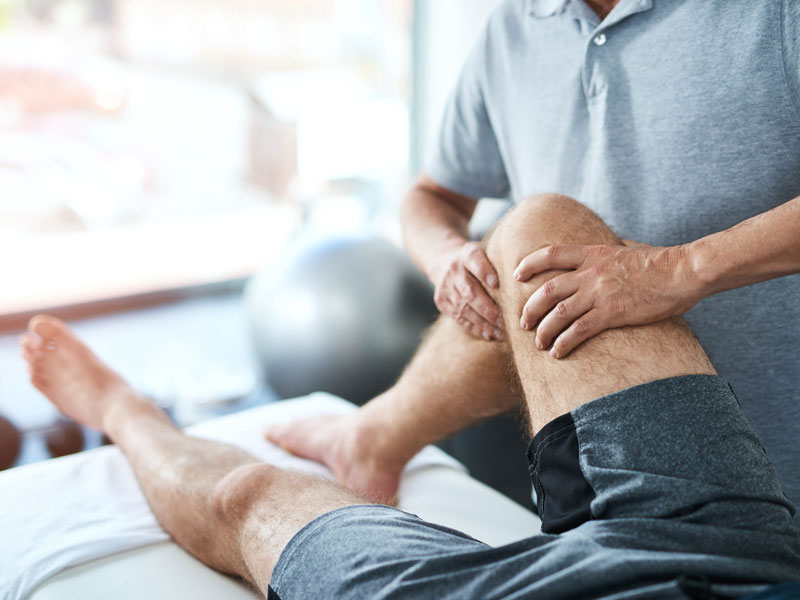 Manuelle Therapie mit gezielter Behandlung am Knie Patient erhält manuelle Therapie am Knie auf einer Liege im Allerfelder Therapiezentrum